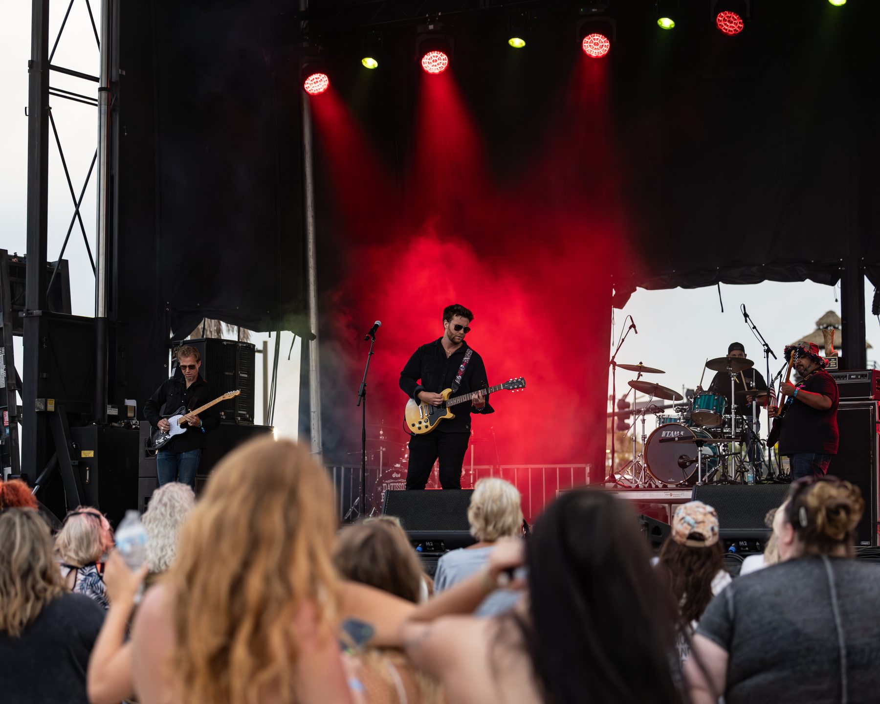 Brian Lawless and his four-piece band playing a festival stage in red light, crowd watching from the barricade
