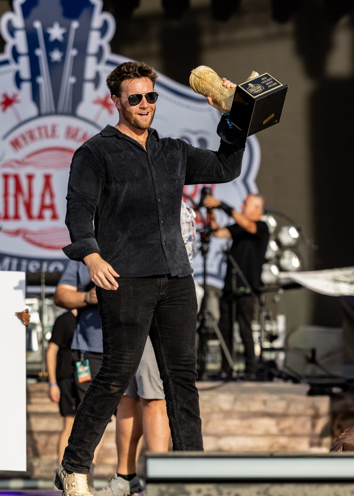 Brian Lawless carrying the Golden Boot trophy across the Carolina Country Music Fest stage in Myrtle Beach, 2026